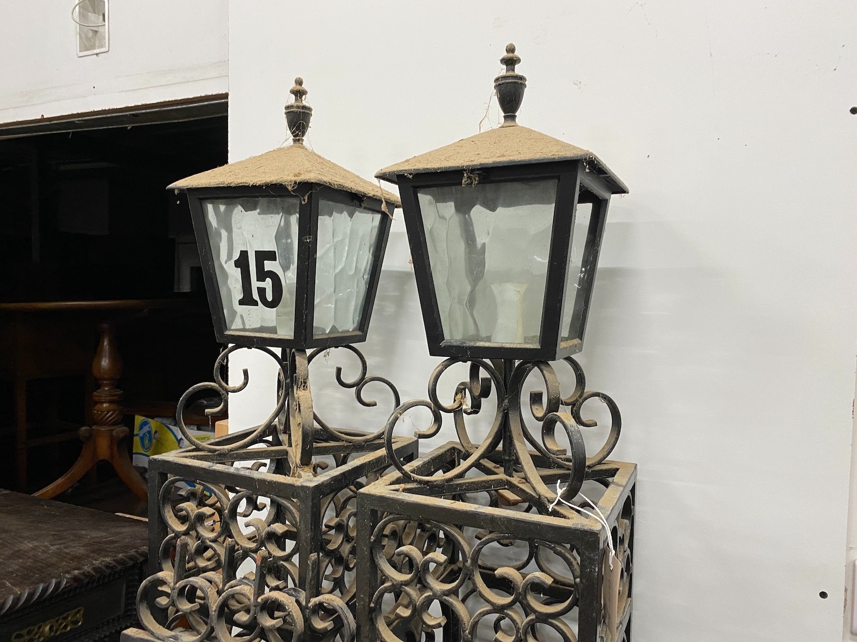 A pair of black painted wrought iron scroll work gates with matching lantern posts, total width 286cm, post height 196cm